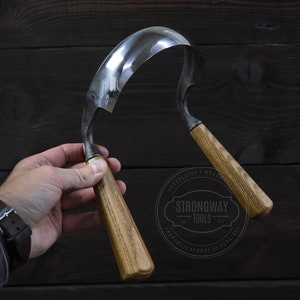 Può includere: Uno strumento da lavoro del legno curvo con due manici in legno. Lo strumento è in metallo e ha una finitura lucida. I manici sono in legno e hanno una finitura naturale. Lo strumento è tenuto in una mano contro uno sfondo in legno scuro. Il testo "Strongway Tools" è visibile nell'immagine.