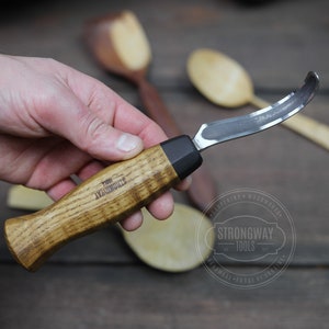 Puede incluir: Una herramienta de talla de madera con una cuchilla curva y un mango de madera. El mango está grabado con las palabras "Strongway Tools".