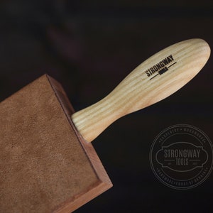 May include: A brown leather burnishing tool with a wooden handle. The handle is engraved with the text "Strongway Tools".