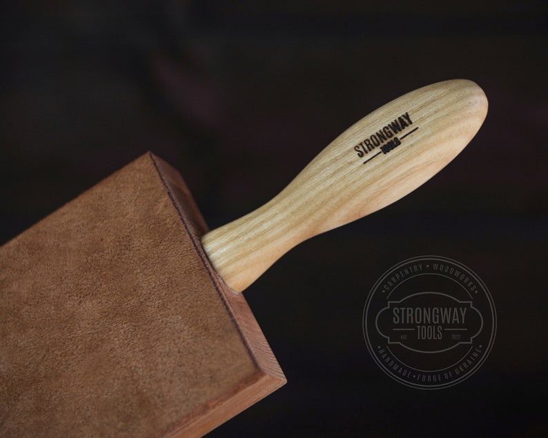 May include: A brown leather burnishing tool with a wooden handle. The handle is engraved with the text "Strongway Tools".