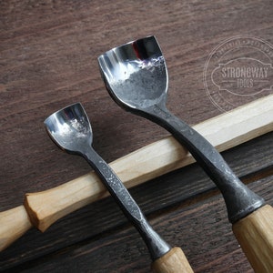 Pu&ograve; includere: Due strumenti per intagliare il legno con manici in legno. Gli strumenti hanno una lama in metallo curva e sono utilizzati per modellare il legno.