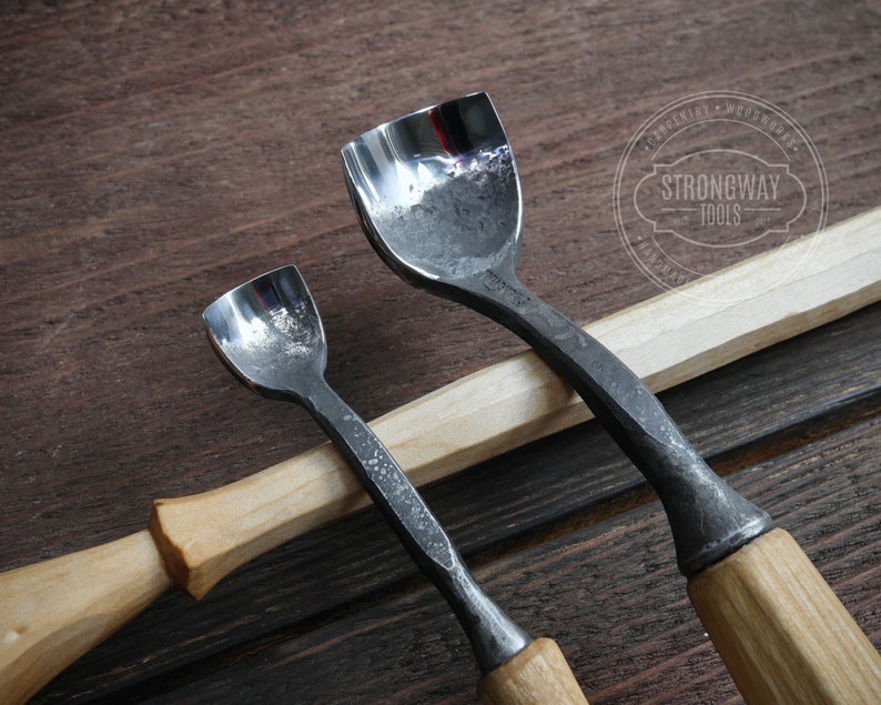 Pu&ograve; includere: Due strumenti per intagliare il legno con manici in legno. Gli strumenti hanno una lama in metallo curva e sono utilizzati per modellare il legno.