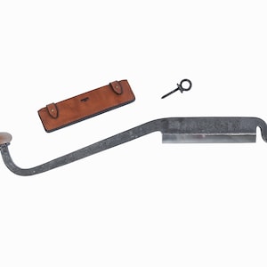 Puede incluir: Un cuchillo de talla de metal negro con mango de madera y funda de cuero. El cuchillo tiene una hoja curva y un gancho en el extremo.