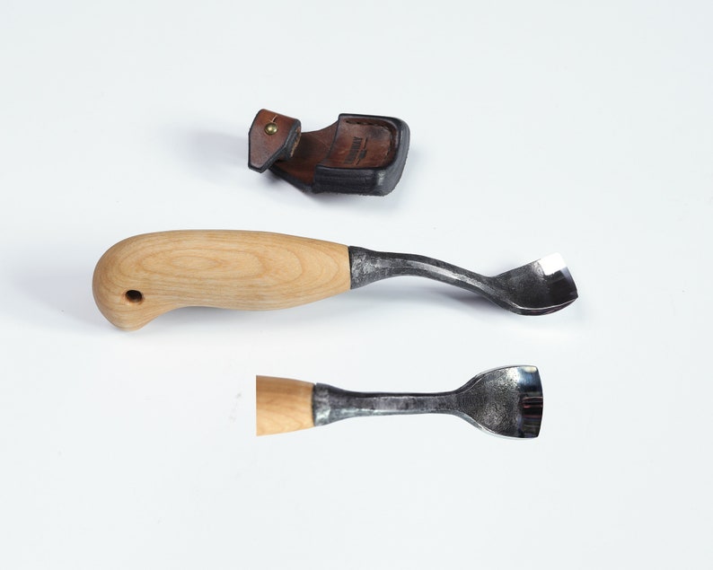 May include: Two wood carving tools with wooden handles and metal blades. The tools are on a white surface. One tool has a curved blade and the other has a straight blade.