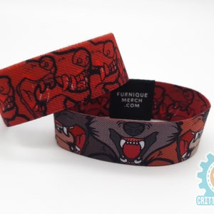 May include: Two red and black woven wristbands with a cartoon wolf design. The wristbands have the text "Furnique Merch .com" printed on them.