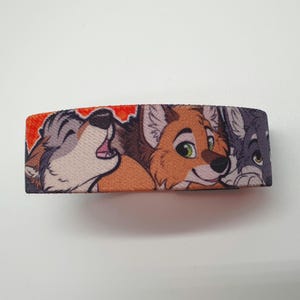 May include: A colorful wristband with a design featuring three cartoon animal faces. The animals are a wolf, a fox, and a dog. The wolf is howling and the fox is smiling. The wristband is made of a soft, comfortable material.