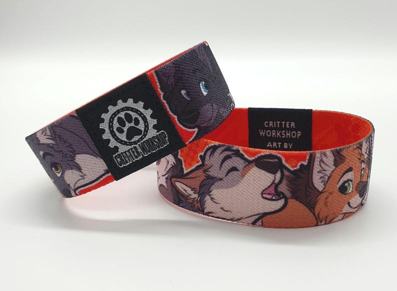 May include: Red, white, and gray woven wristband with a black and gray logo that says "Critter Workshop Art By". The wristband features a cartoon image of three furry animals.