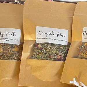 Puede incluir: Tres bolsas de papel marrón con etiquetas y hierbas secas en su interior. Las etiquetas dicen "Crabby Pants", "Complete Bliss" y "Renew & Refresh".