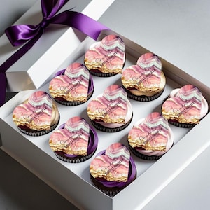 May include: A box of cupcakes decorated with heart-shaped toppers featuring a pink and gold marble design. The toppers have the text "Samantha's Bridal Shower" printed on them.