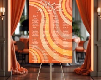 May include: A wedding seating chart on an easel. The chart features a retro design with orange, peach, and cream-colored curved stripes. The text reads "Celebrating the Love of Ashley and Charlie" and lists guest names by table.