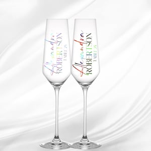 Puede incluir: Dos copas de champán con texto en arcoíris que dice "Alexandra Robertson | TABI | 25".