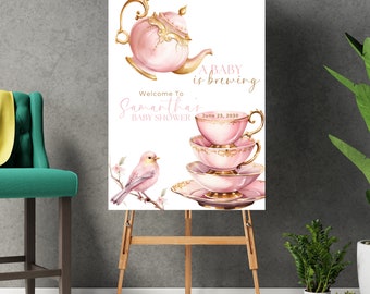 Może przedstawiać: Różowo-złoty znak na baby shower z filiżanką do herbaty i czajnikiem, z tekstem "A baby is brewing" i "Welcome to Samantha's Baby Shower" z datą 23 czerwca 2030.