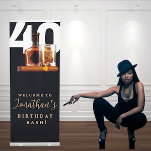 Può includere: Un banner nero con il numero 40 e un'illustrazione di una bottiglia di whisky, un bicchiere e un sigaro. Il testo recita "WELCOME TO Jonathan's BIRTHDAY BASH!" Una persona in abito e cappello neri è nell'immagine.