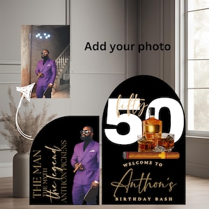 Può includere: Uno sfondo per feste di compleanno nero e dorato con un grande numero 50 bianco, le parole "fifty" e "Anthon's Birthday Bash", e una bottiglia di whisky e bicchieri. Lo sfondo è decorato con un sigaro dorato e una freccia dorata che punta a uno spazio per una foto.