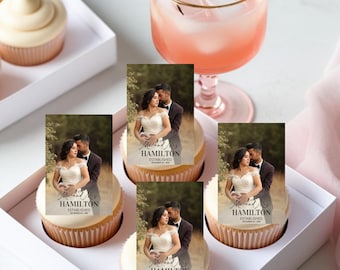 Puede incluir: Cupcakes con glaseado blanco y adornos fotográficos con una pareja. Los adornos dicen "Mr. and Mrs. Hamilton Established September 26, 2020." También se ve un vaso de bebida rosa con cubitos de hielo.