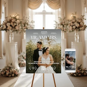 以下が含まれることがあります： イーゼルに立てられた結婚式のサイン。テキストは「Mr. and Mrs. Martinez」です。サインにはカップルの写真とQRコードが含まれています。スマートフォンにも同様の画像が表示されています。背景にはフラワーアレンジメントと結婚式場があります。