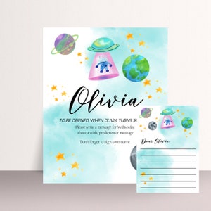 May include: A blue and white watercolor background with gold stars. A pink and white spaceship with a blue robot inside. The text "Olivia" is written in black cursive. The text "TO BE OPENED WHEN OLIVIA TURNS 18" is written in black. The text "Please write a message for Wednesday share a wish, prediction or message Don't forget to sign your name" is written in black. A smaller card with the text "Dear Olivia." is on the right side of the image.