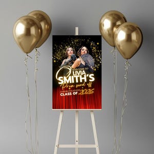 May include: A sign for a prom send-off, featuring the text "Welcome to Livia Smith's Prom send off, Congratulations Class of 2026." The sign is on an easel, with gold balloons on either side. The background is a red curtain.