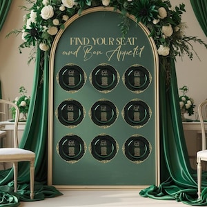 May include: A wedding seating chart with a dark green background and gold trim. The chart features nine black plates with gold lettering, each displaying table assignments. The text "Find Your Seat and Bon Appetit" is displayed at the top, with floral arrangements.
