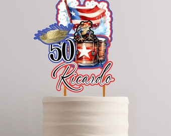May include: A cake topper with a red, white, and blue Puerto Rican flag, a green and red frog, a drum, a straw hat, and the text "50 Ricardo".