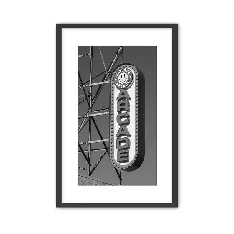 A framed, black and white photograph of a vintage arcade sign on the Wildwood, NJ Boardwalk with gritty industrial details. Photography by Thomas Enson.
