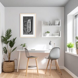 A black and white photograph of a vintage arcade sign on the Wildwood, NJ Boardwalk hangs on a wall above a desk in a home office.