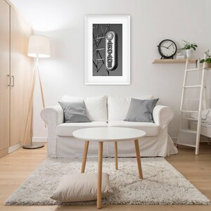 A black and white photograph of a vintage arcade sign on the Wildwood, NJ Boardwalk hangs on a wall behind a sofa in an apartment living room.