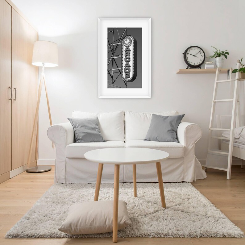 A black and white photograph of a vintage arcade sign on the Wildwood, NJ Boardwalk hangs on a wall behind a sofa in an apartment living room.