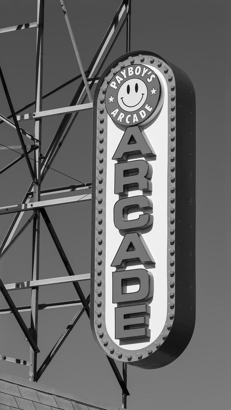 A black and white photograph of a vintage arcade sign on the Wildwood, NJ Boardwalk with gritty industrial details. Photography by Thomas Enson.