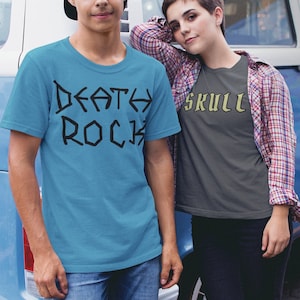 May include: Two people wearing graphic t-shirts. The person on the left is wearing a light blue t-shirt with the text "DEATH ROCK" in black. The person on the right is wearing a dark gray t-shirt with the text "SKULL" in yellow.