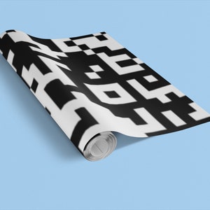 Könnte beinhalten: Eine Rolle schwarzes und weißes Geschenkpapier mit Muster. Das Papier hat ein geometrisches Design mit Quadraten und Rechtecken.