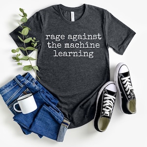 Könnte beinhalten: Ein dunkelgraues T-Shirt mit dem Aufdruck "rage against the machine learning" in weiß.
