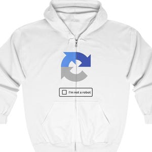 Può includere: Felpa con cappuccio bianca con zip, con un'icona circolare blu e grigia e il testo "Non sono un robot" in un riquadro bianco.