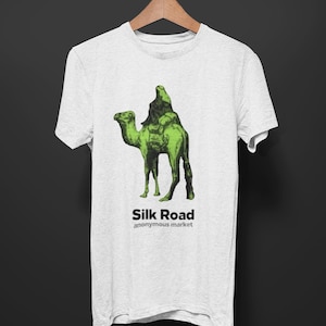 Könnte beinhalten: Ein weißes T-Shirt mit einem grünen Bild einer Person, die auf einem Kamel reitet. Der Text "Silk Road anonymous market" ist unter dem Bild gedruckt.