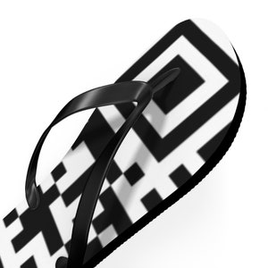 Op de afbeelding: Zwarte slippers met een wit en zwart geometrisch patroon.