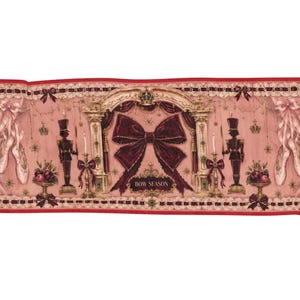 May include: A rectangular fabric runner featuring a pink background with a central dark red bow and the text BOW SEASON. The design includes illustrations of ballet slippers, nutcracker figures, candelabras, and draped curtains with red trim.