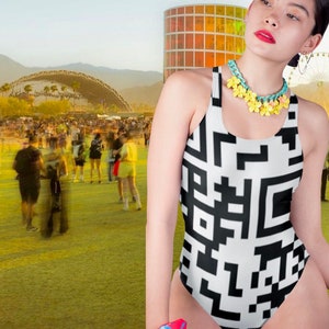 Op de afbeelding: Een zwart-witte badpak met een geometrisch patroon. Het badpak heeft een ronde hals en een racerback-stijl. Het model draagt een gele bloemenketting.