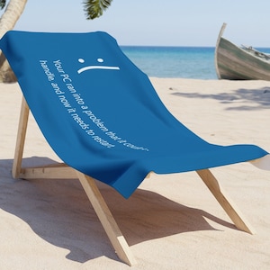 May include: A blue beach towel with the text "Your PC ran into a problem that it can't handle and now it needs to restart" and a sad face emoji.