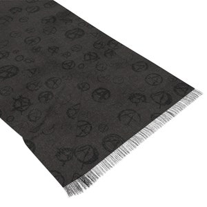 May include: A black scarf with a repeating pattern of a stylised symbol. The scarf has a fringed edge.