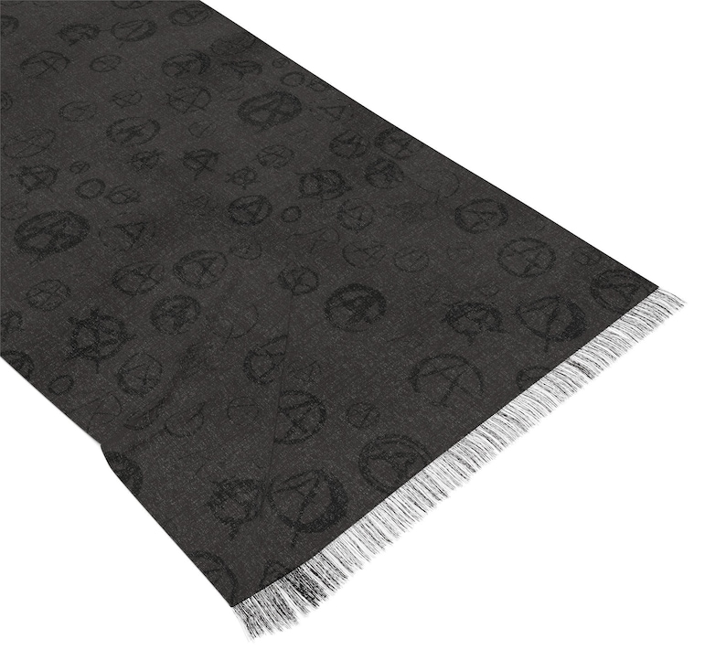 May include: A black scarf with a repeating pattern of a stylised symbol. The scarf has a fringed edge.