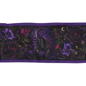 Puede incluir: Una bufanda rectangular con una paleta de colores morado oscuro y negro. El diseño muestra un escorpión negro central rodeado de rosas moradas y rojas, enredaderas espinosas y motivos de media luna, con flecos en ambos extremos.