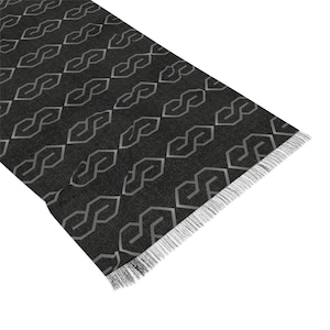 May include: Black scarf with a geometric pattern of interlocking gray shapes. The scarf has a fringed edge.
