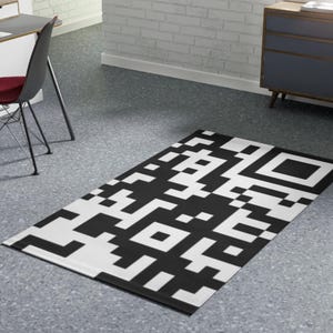 Puede incluir: Alfombra en blanco y negro con un patrón de código QR. La alfombra está sobre un suelo gris.