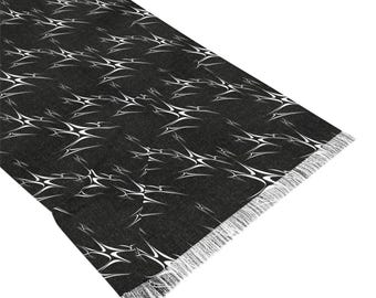 May include: Black scarf with a white abstract pattern. The scarf has a fringed edge.
