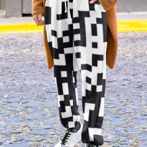 May include: Black and white pixelated pattern sweatpants with a drawstring waist.