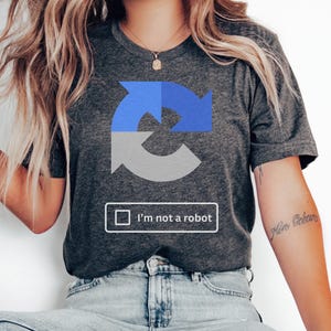 May include: A dark gray t-shirt with a blue and gray circular graphic and the text "I'm not a robot".