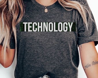 Könnte beinhalten: Ein dunkelgraues T-Shirt mit dem Wort "TECHNOLOGY" in Weiß auf der Vorderseite. Das Wort ist von einem grünen digitalen Code-Muster umgeben.