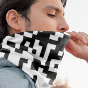 May include: A person wearing a white and black patterned neck gaiter. The gaiter is made of a soft, breathable fabric and is designed to be worn around the neck or face.