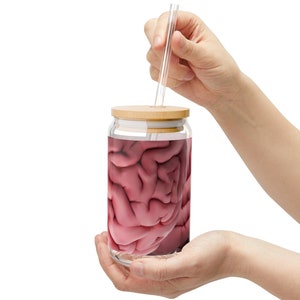 Op de afbeelding: Een glazen pot met een houten deksel en een doorzichtige drinkrietje. De pot is gevuld met een roze vloeistof die lijkt op een hersenen.