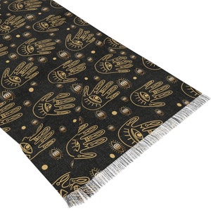 May include: Black and gold rug with a repeating pattern of hands with eyes and small circles. The rug has a fringe border.
